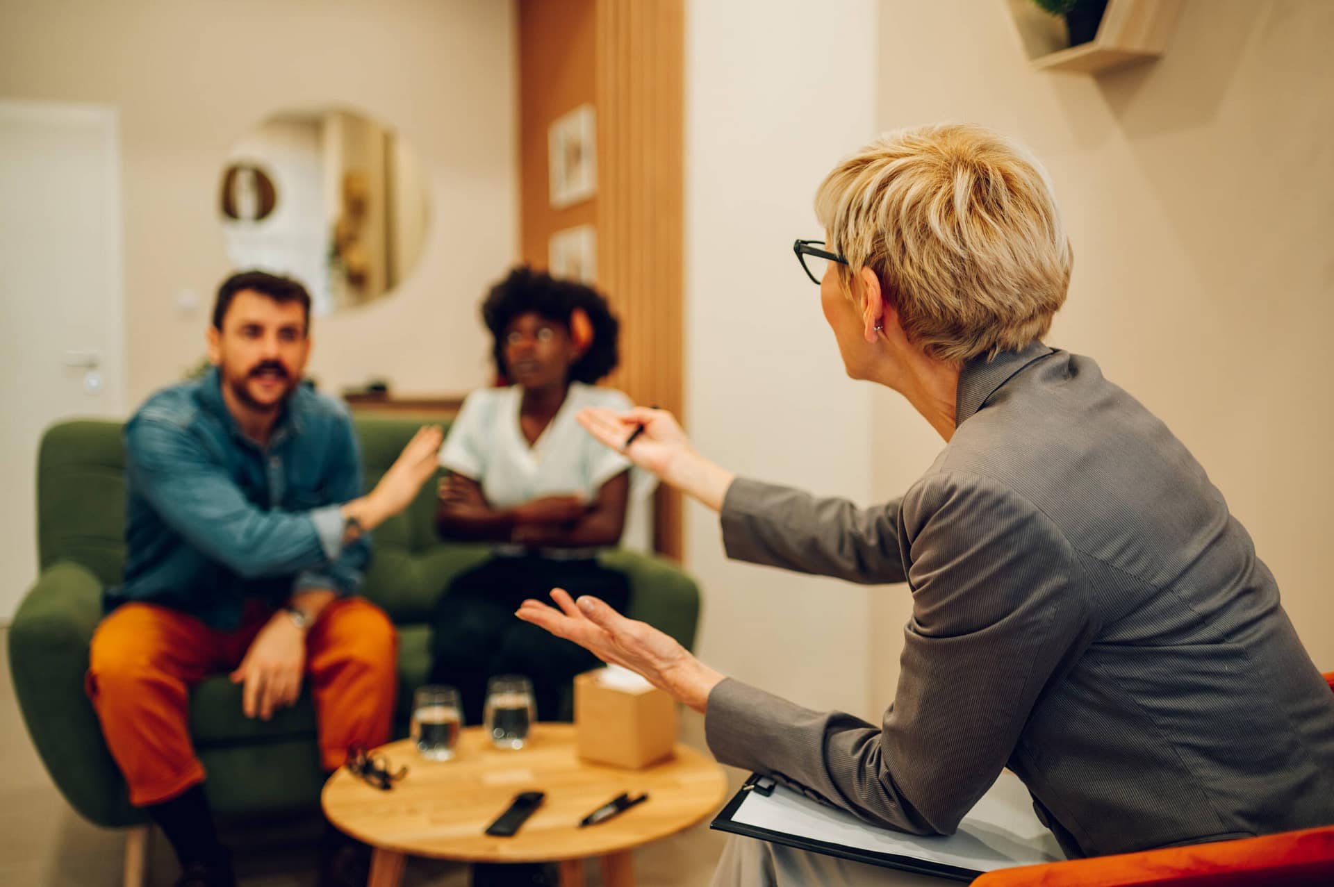 Diverse couple on a therapy session in a psychologist office Multiracial boyfriend and girlfriend or spouses meeting therapist or counseling psychologist in an office. Focus on a rear view of a couple therapist. Copy space.