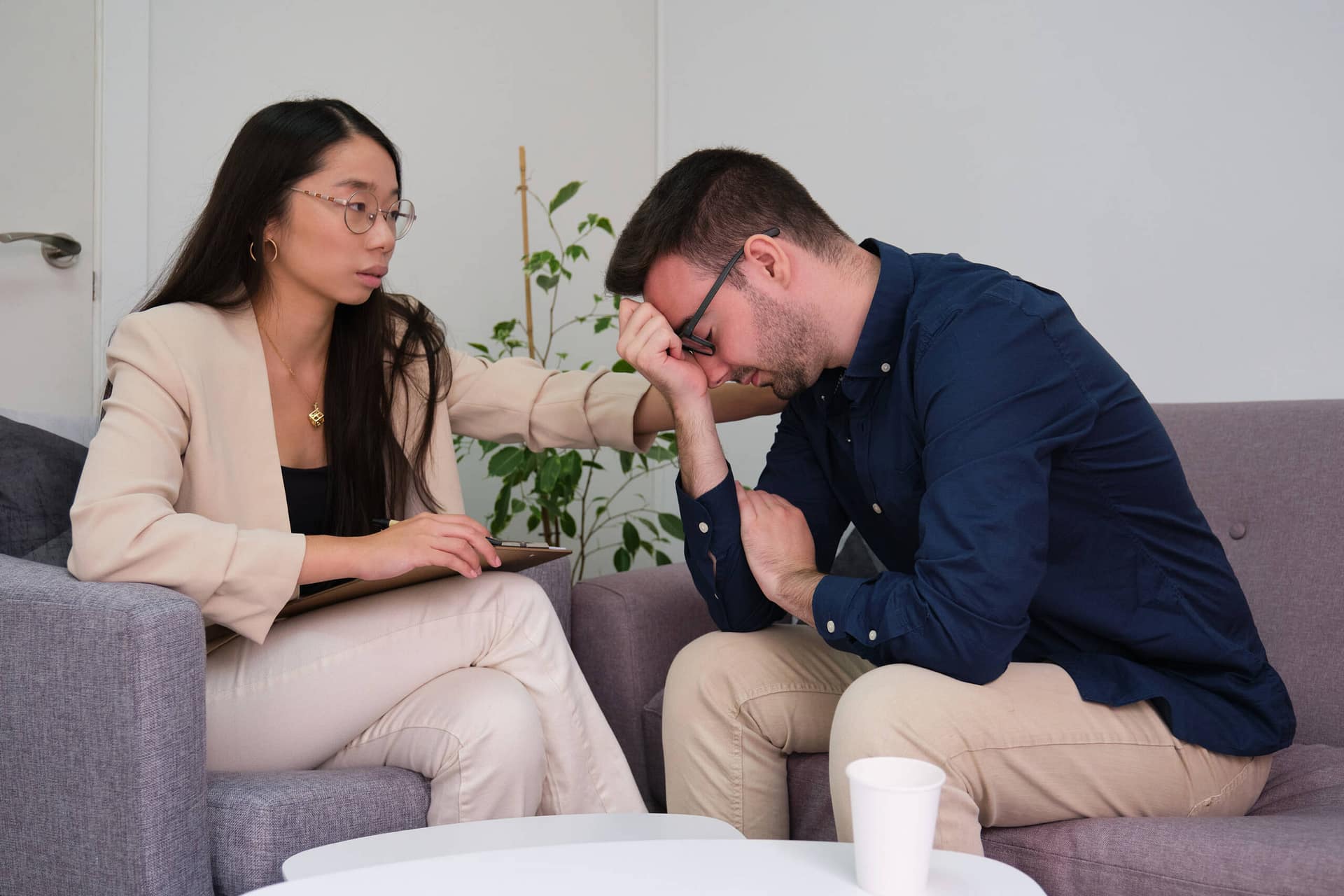Asian female psychologist comforting her caucasian man patient at therapy. Asian female psychologist comforting caucasian man patient at therapy. Mental health concept.