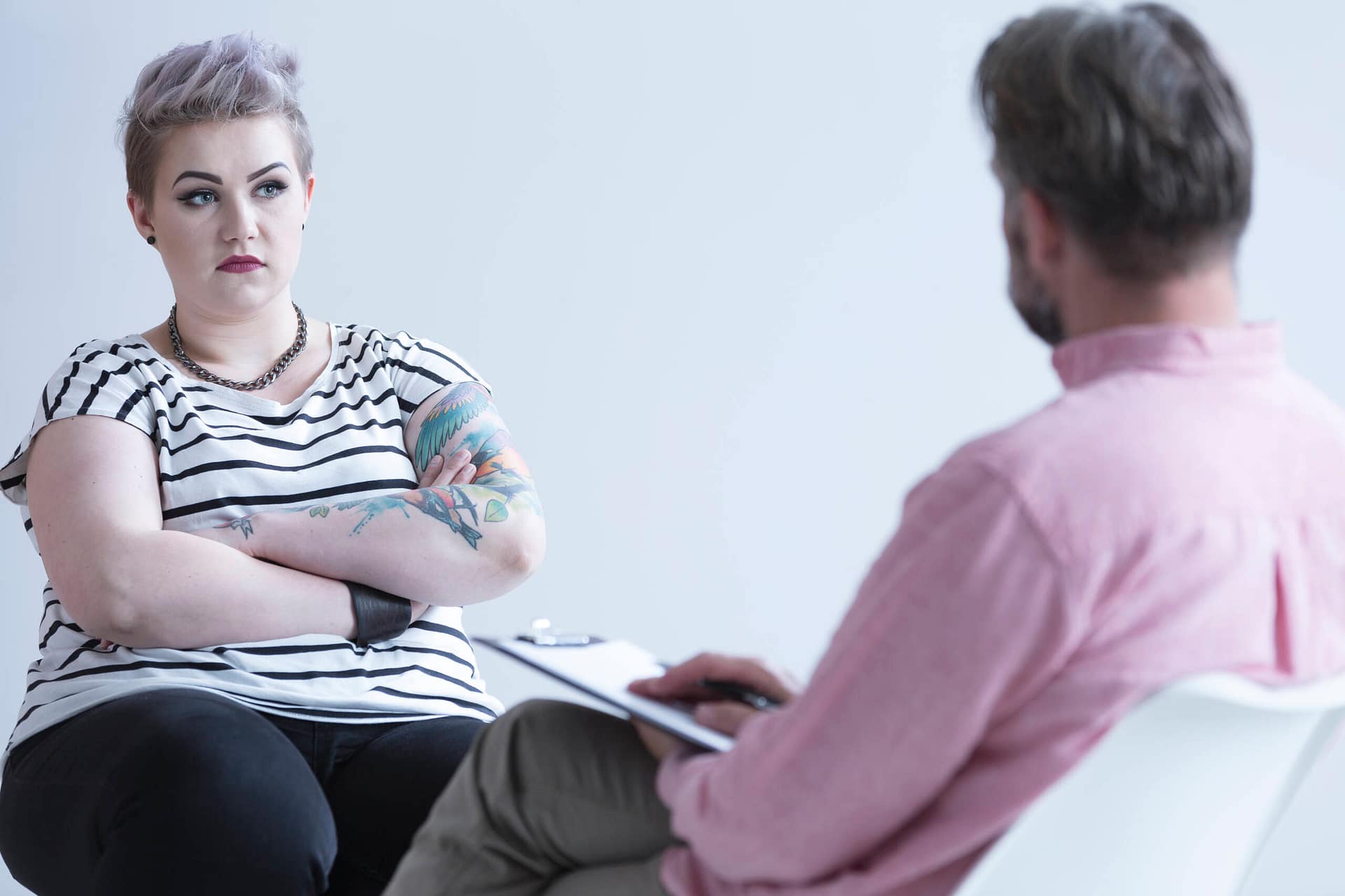 Troubled girl with tattoo Troubled girl with tattoo and dark makeup talking with psychologist