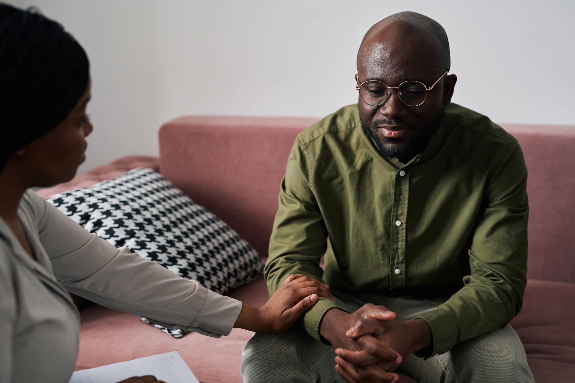 Young depressed mn sitting on couch while counselor comforting him Young depressed mn sitting on couch and describing his psychological problems during session while counselor comforting him